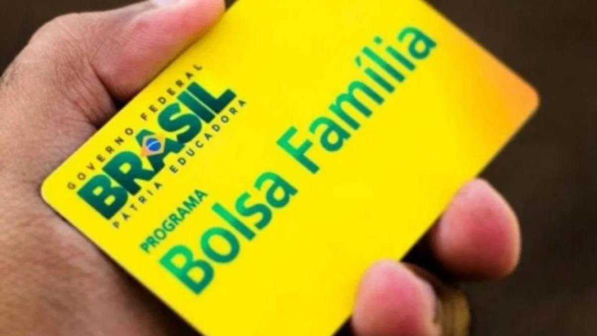 Cartão do Bolsa Família em primeiro plano com gráfico de queda e família que acaba de conseguir emprego formal ao fundo